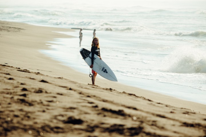 a man standing on top of a sandy beach next to the ocean