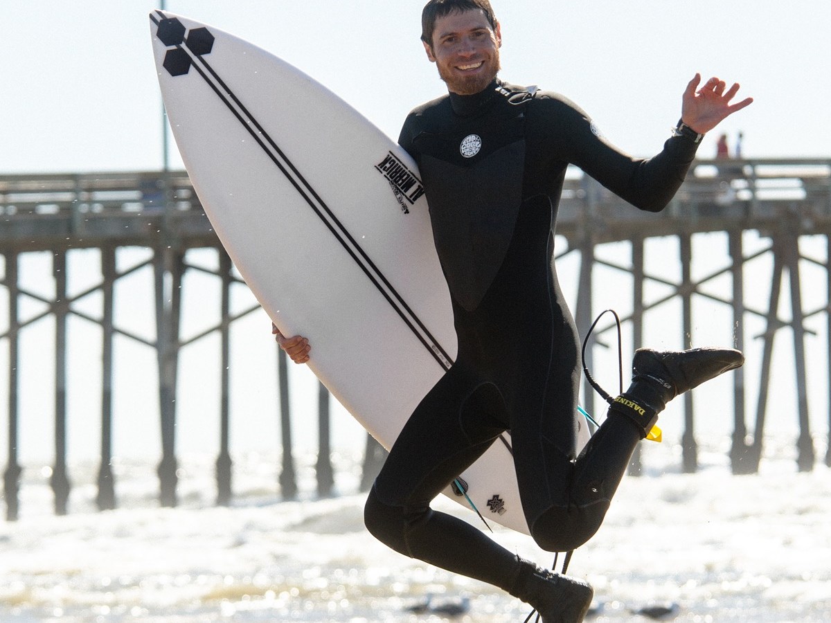 a man in a wet suit carrying a surf board