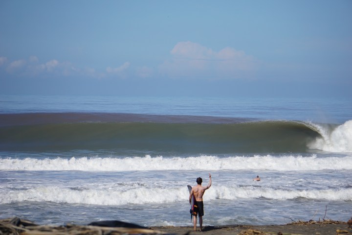 a man walking across a beach next to the ocean